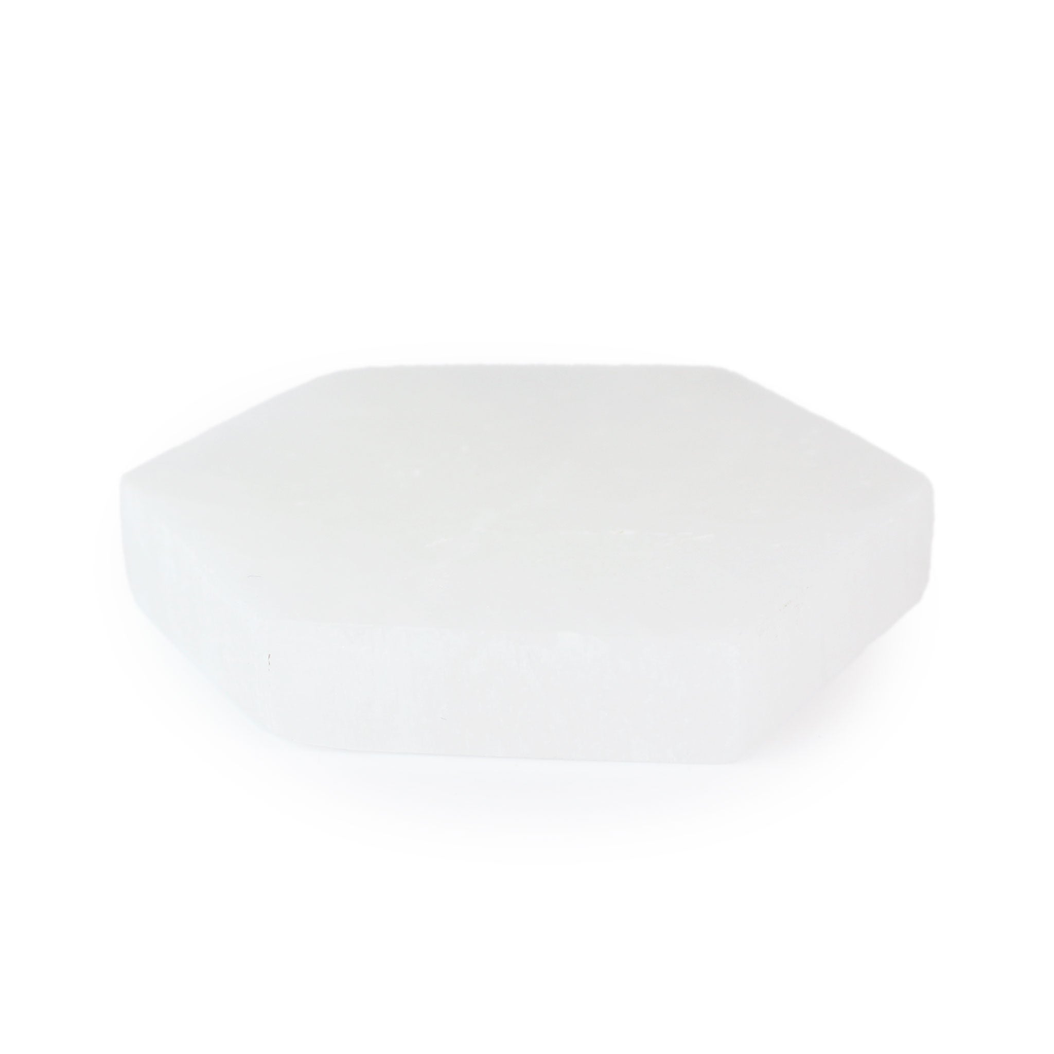 Angled view of a hexagonal selenite coaster displaying its luminous surface and edges, highlighting the crystal’s soft sheen.