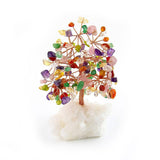 Copper tree with gemstone leaves in the seven chakra colors, rooted in a white crystal base for home decor.