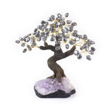 Large hematite bonsai tree sculpture with polished gemstone leaves on amethyst foundation.