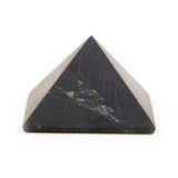 Shungite pyramid on white background, side view showing unpolished stone surface.
