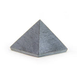 Unpolished soapstone pyramid on white background, angled view showing natural texture and soft tones.